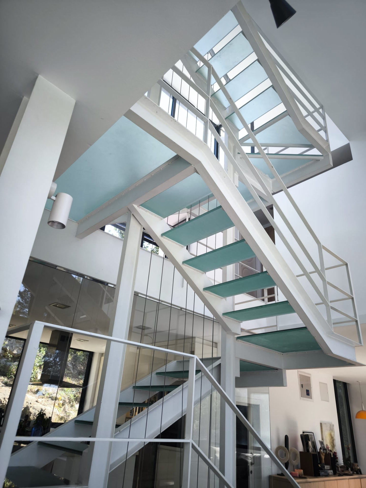 White steel and glass staircase rising through the house